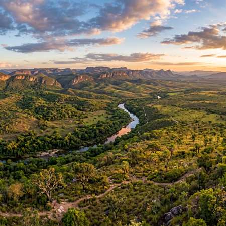 Winding river through green valleys with rugged mountains at sunset